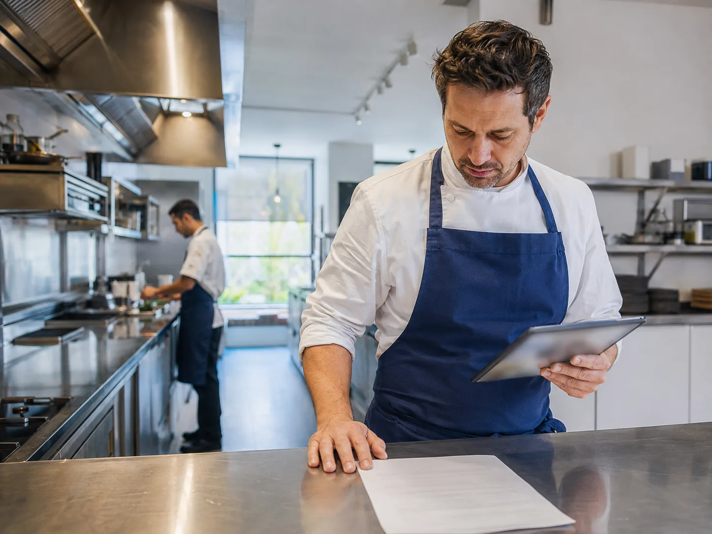 Manager kuchni porównujący tablet z papierową dokumentacją HACCP